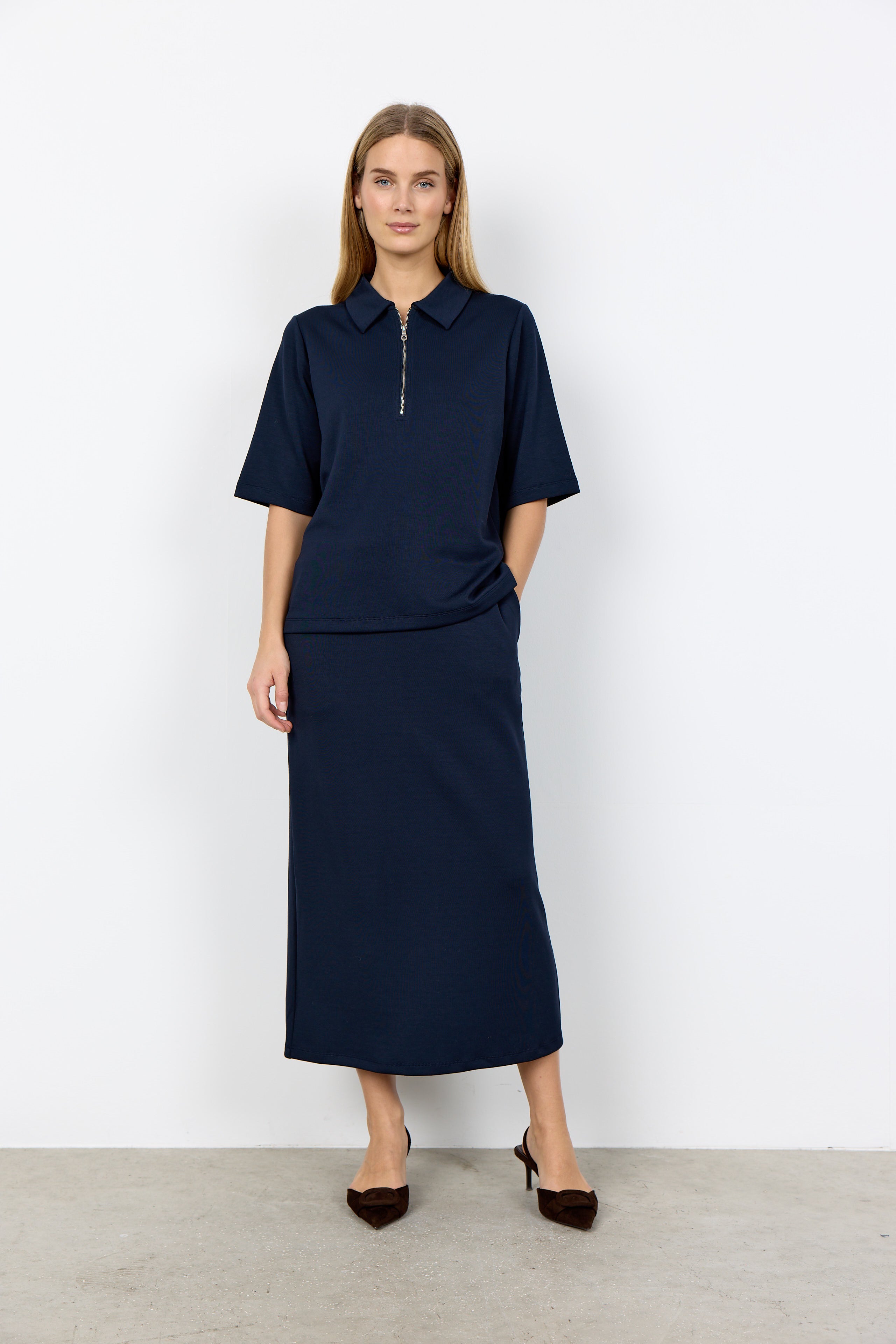 Woman wearing a navy blue outfit with a skirt and top against a white background