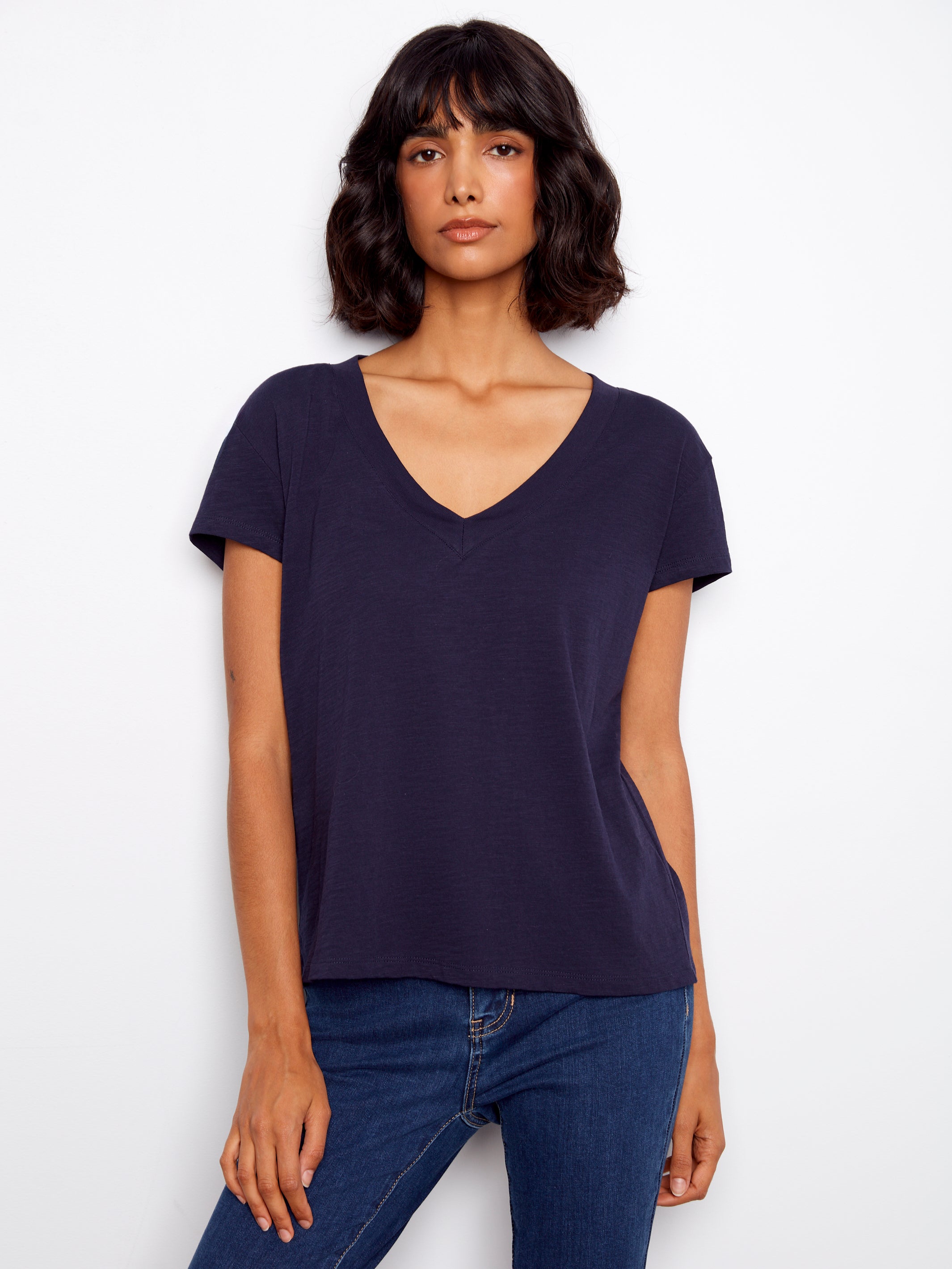 Woman wearing a navy blue t-shirt and jeans on a white background