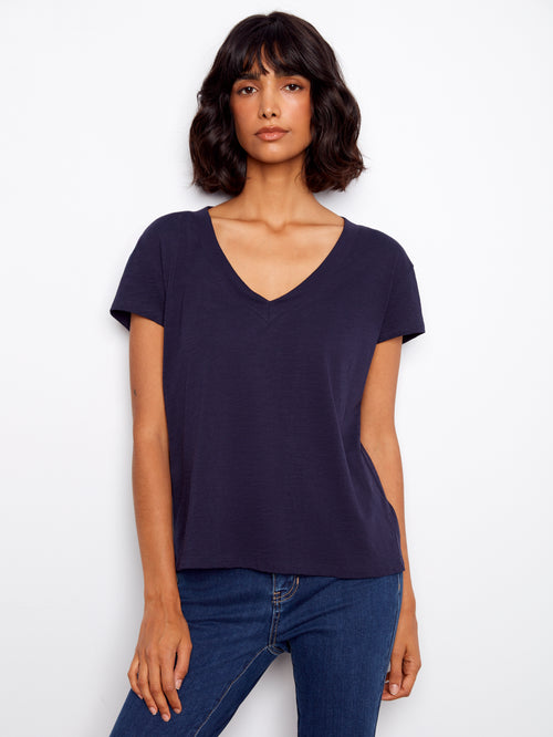 Woman wearing a navy blue t-shirt and jeans on a white background