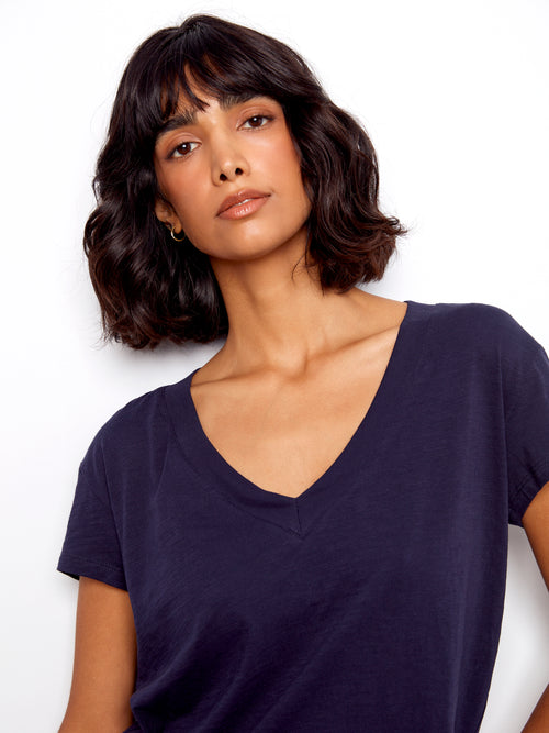 Woman wearing a dark blue V-neck shirt against a white background