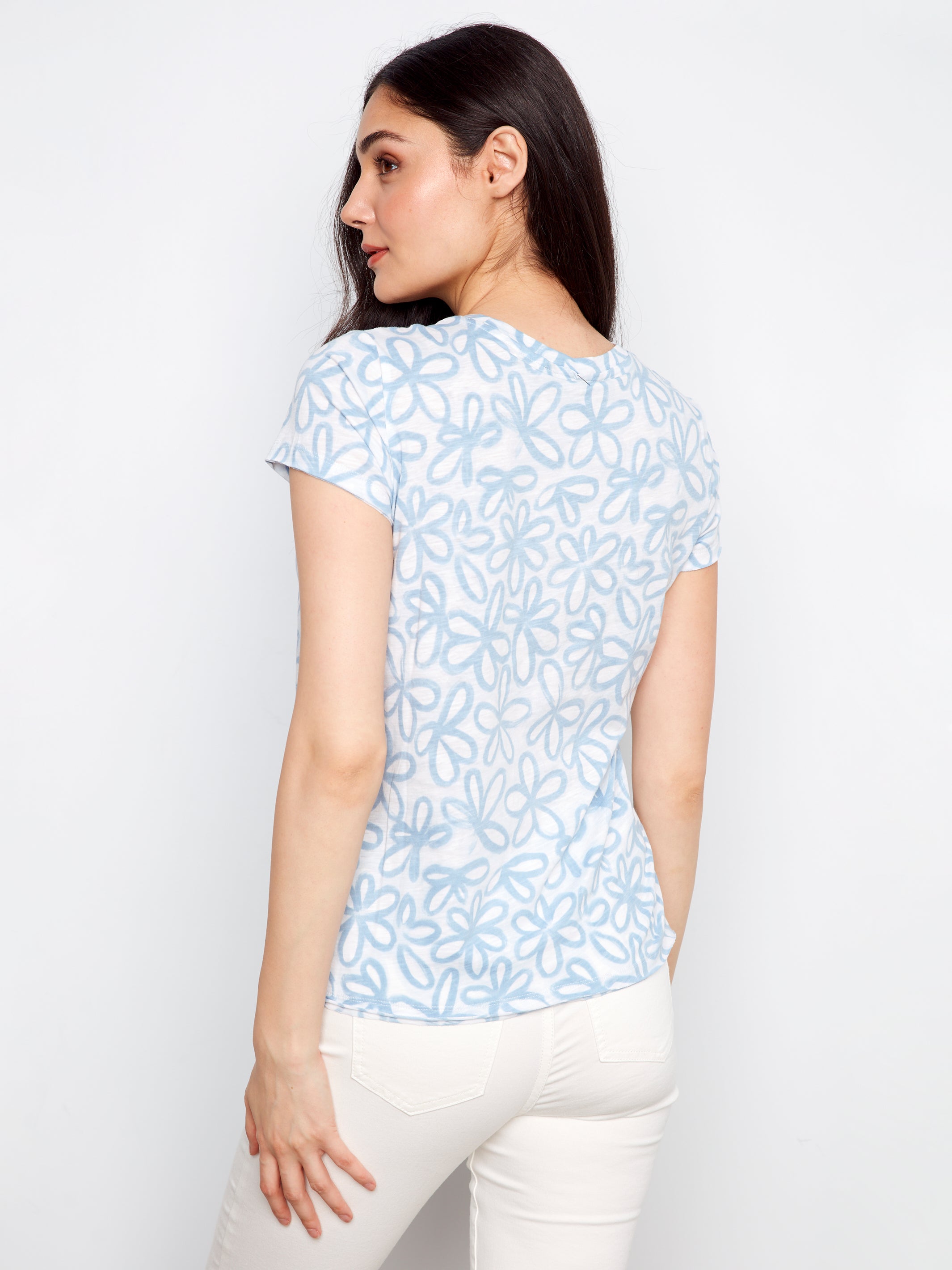 Woman wearing a light blue floral patterned shirt against a white background