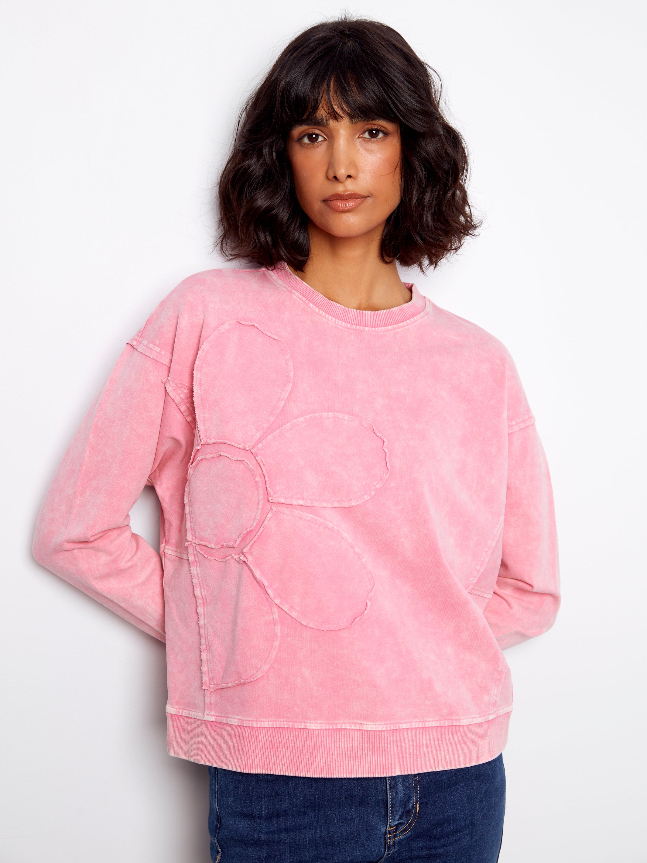 Person wearing a pink sweatshirt with a heart design on a white background