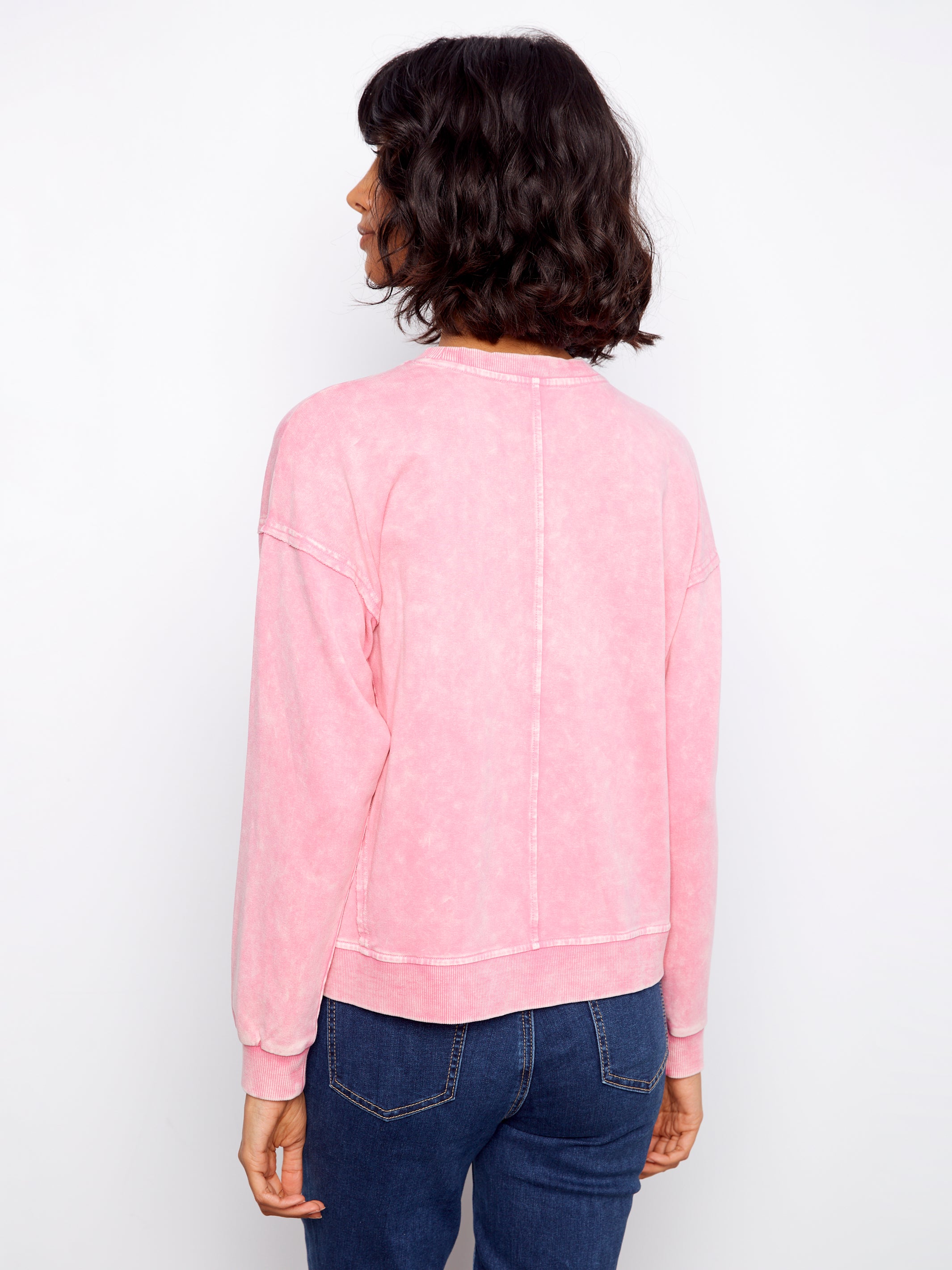 Person wearing a pink sweatshirt and blue jeans on a white background