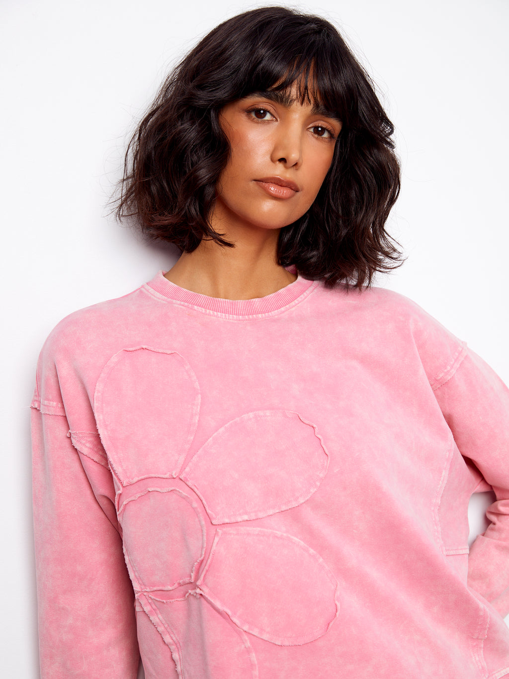 Person wearing a pink sweatshirt with a design on a white background