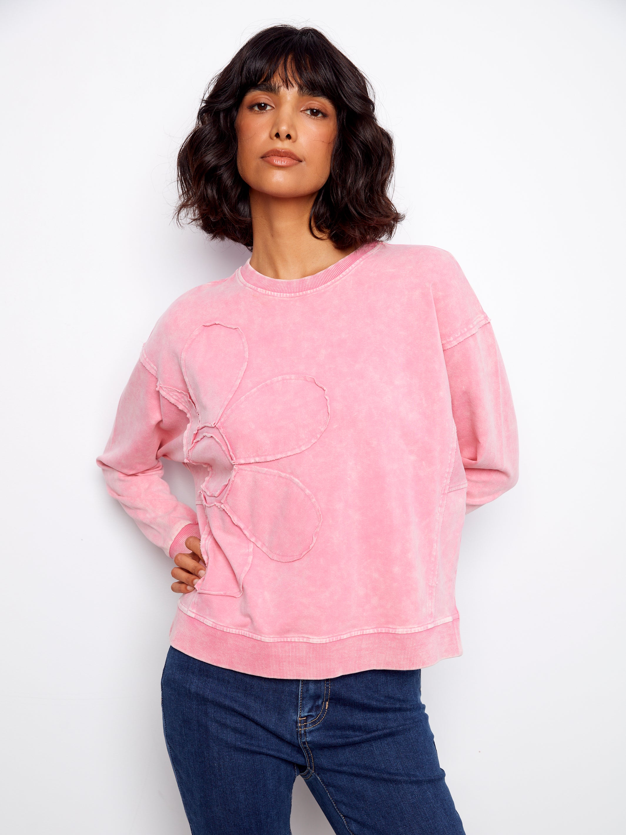 Woman wearing a pink sweatshirt with a heart design on a white background