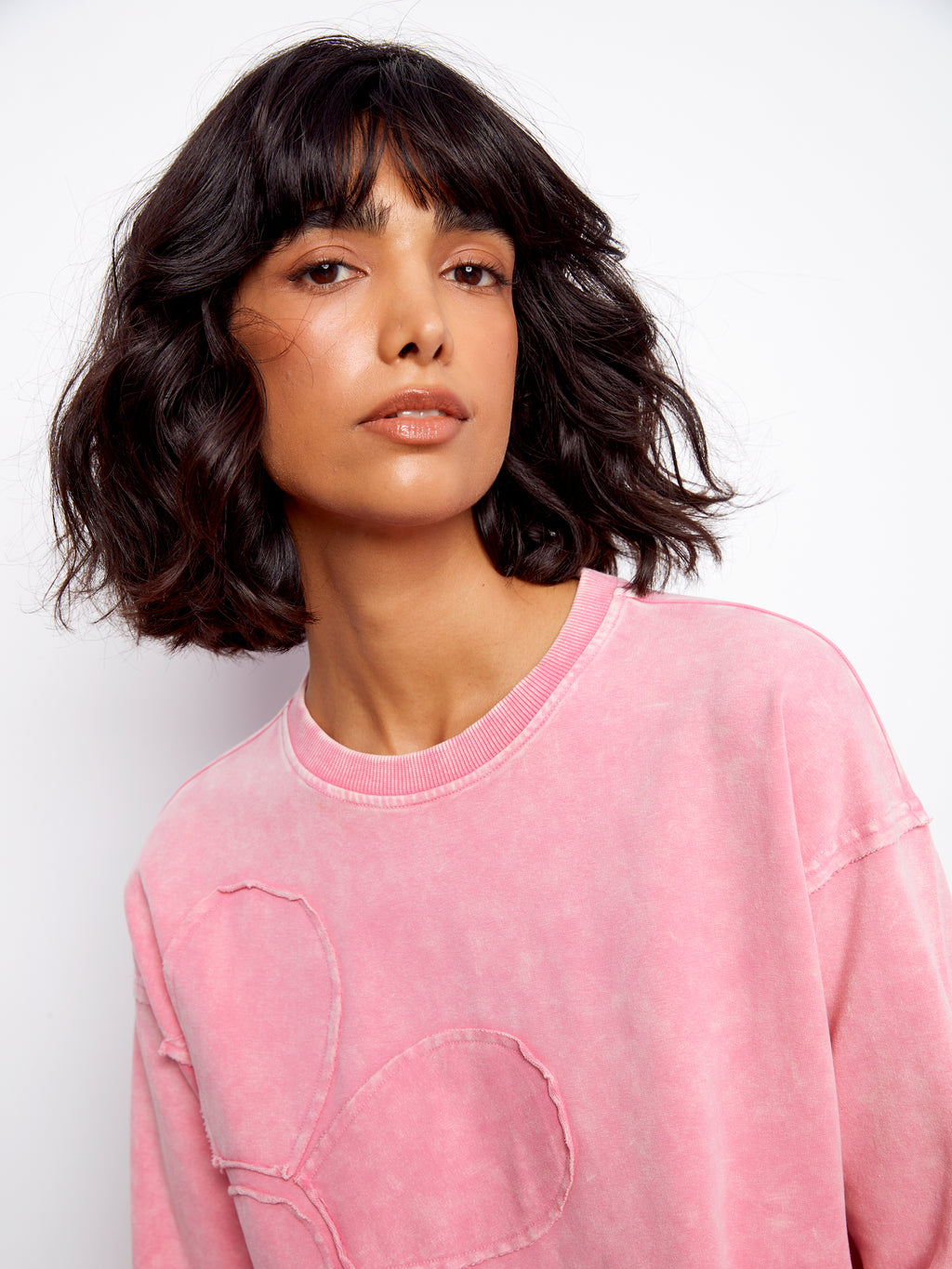 Woman wearing a pink sweatshirt against a white background