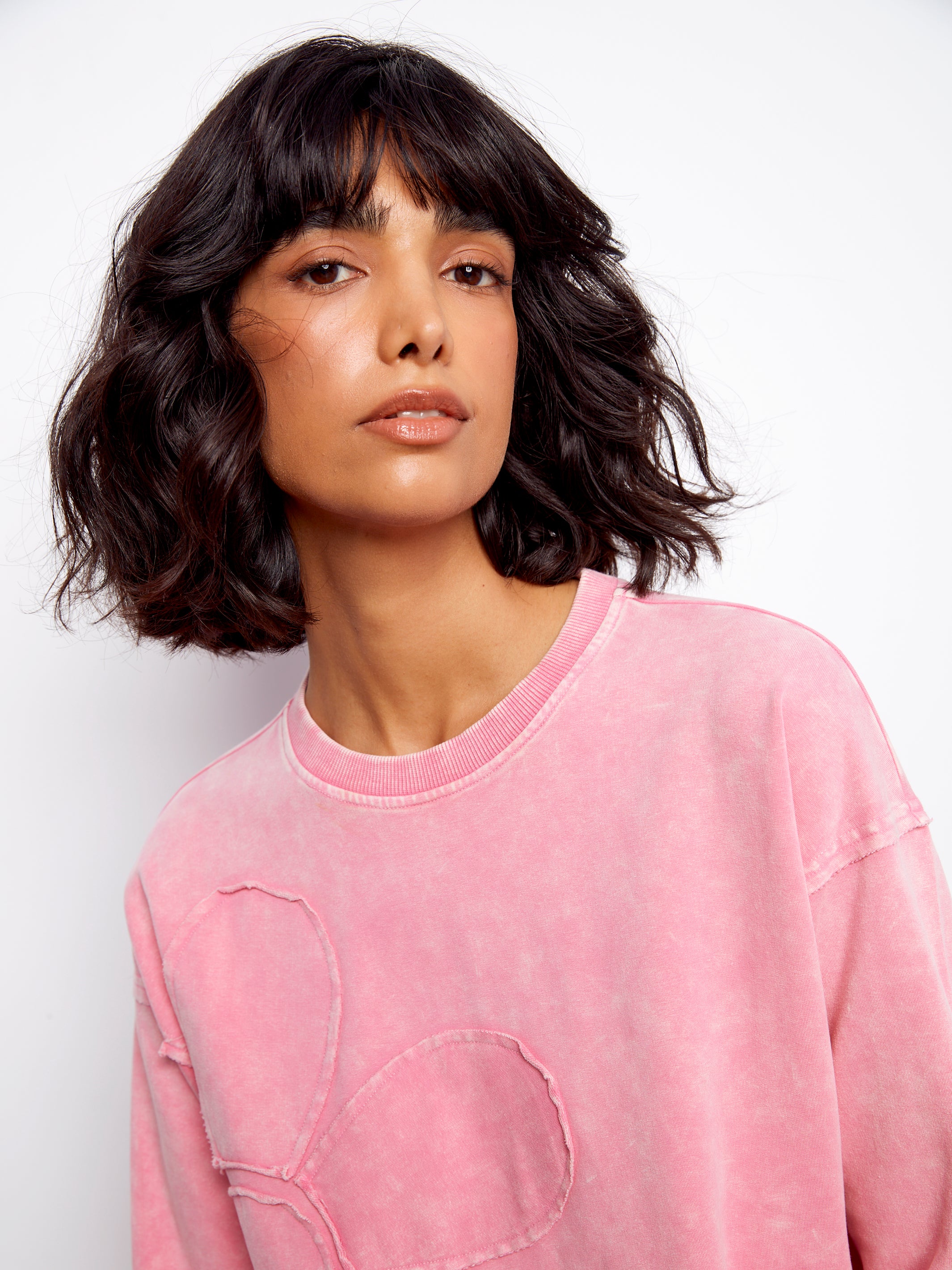 Woman wearing a pink sweatshirt against a white background