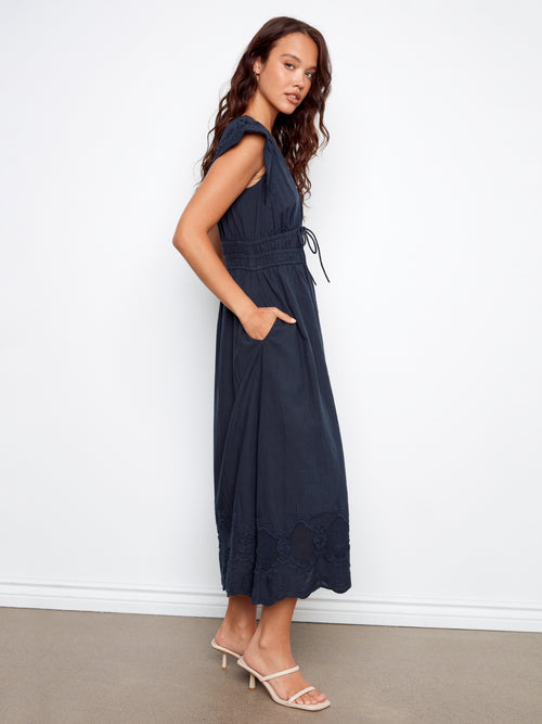 Woman wearing a navy blue sleeveless dress against a white background
