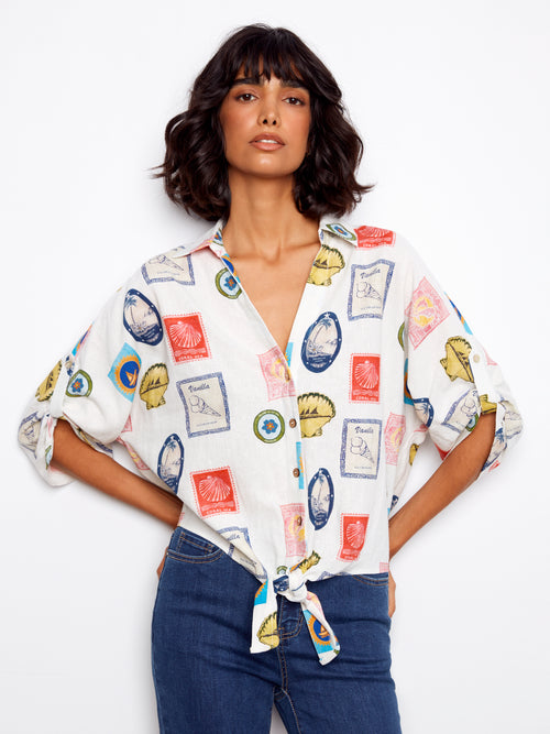 Woman wearing a colorful patterned shirt with rolled-up sleeves on a white background