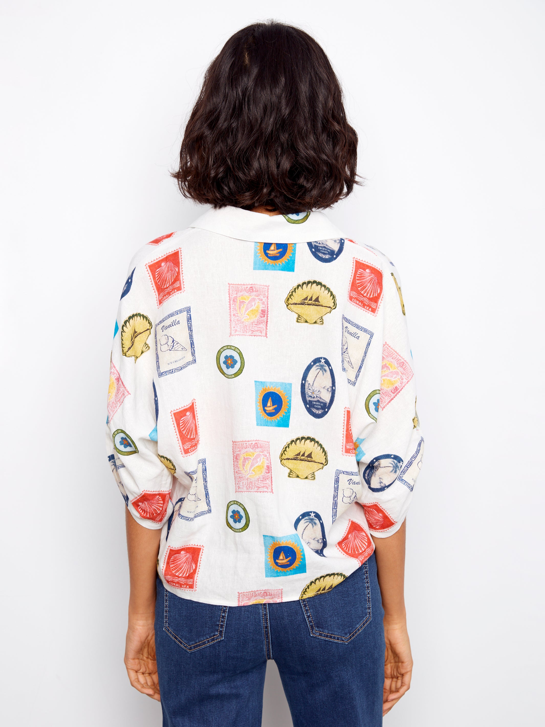 Person wearing a white shirt with colorful graphic designs on a plain background