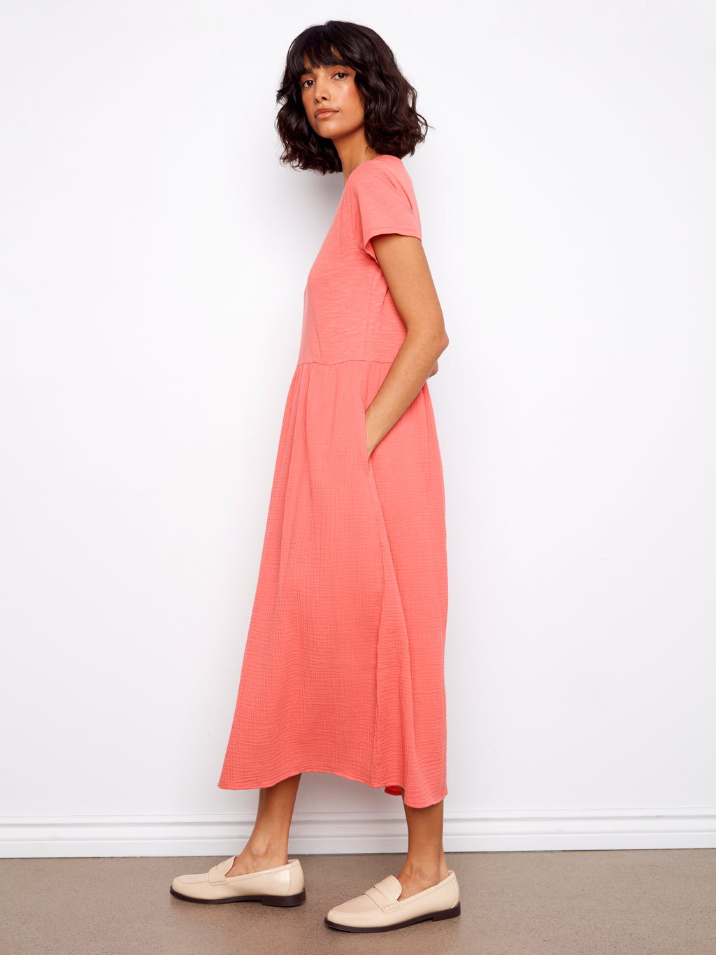 Woman wearing a pink dress standing against a white wall