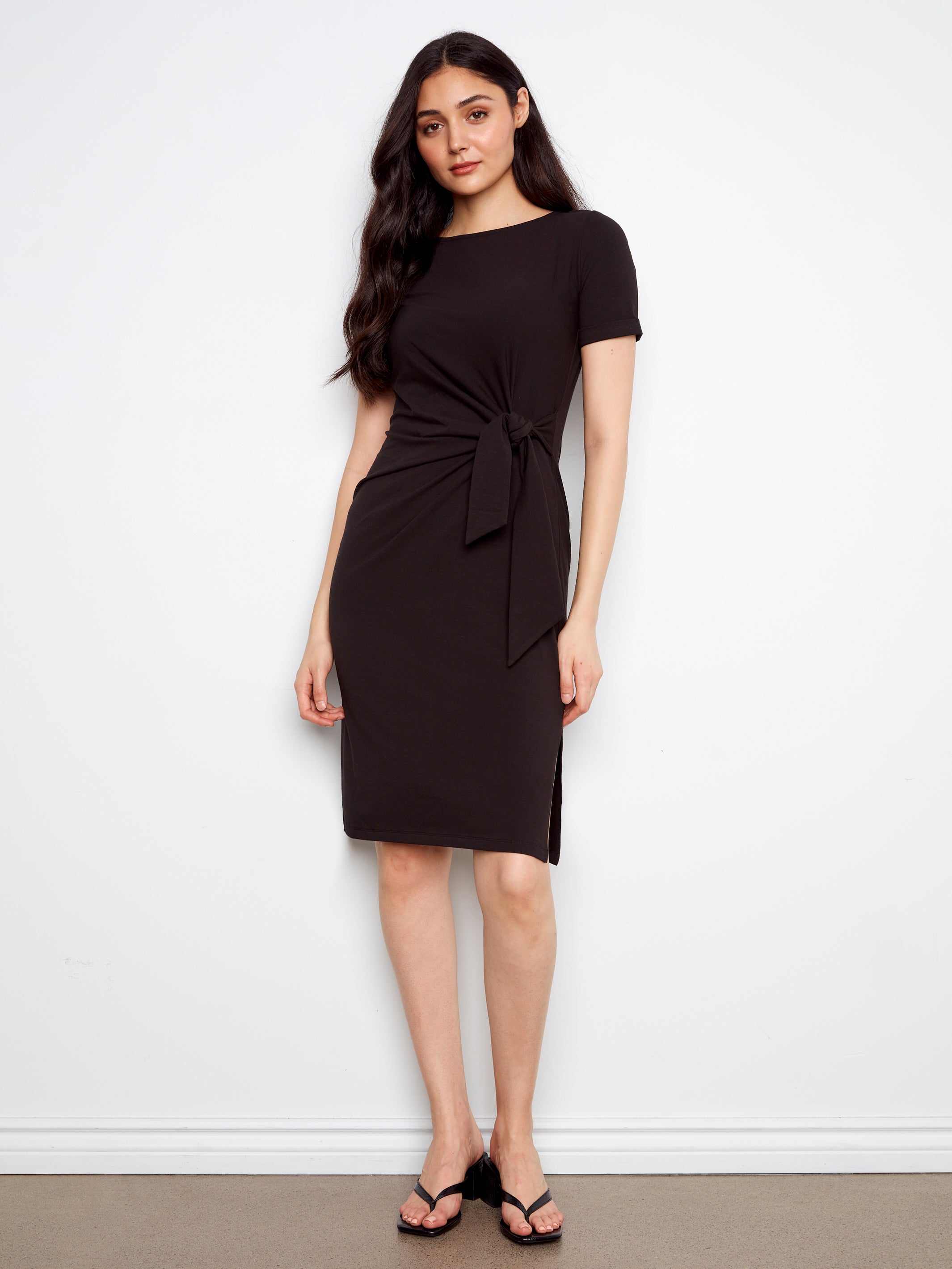 Woman wearing a black dress with a knot detail on a white background