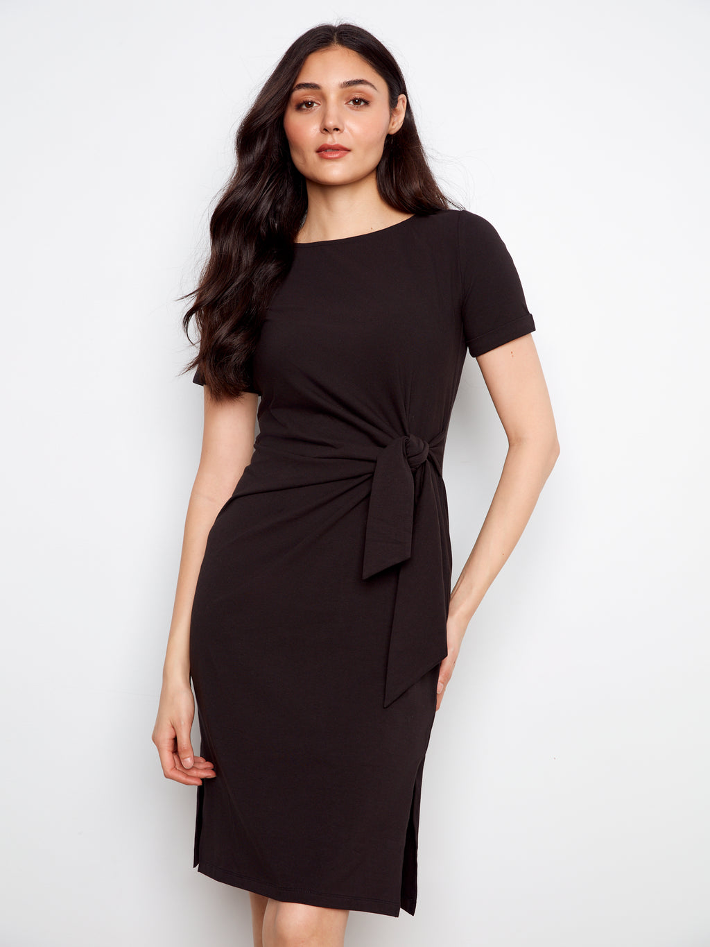 Woman wearing a black dress with a tie waist on a white background