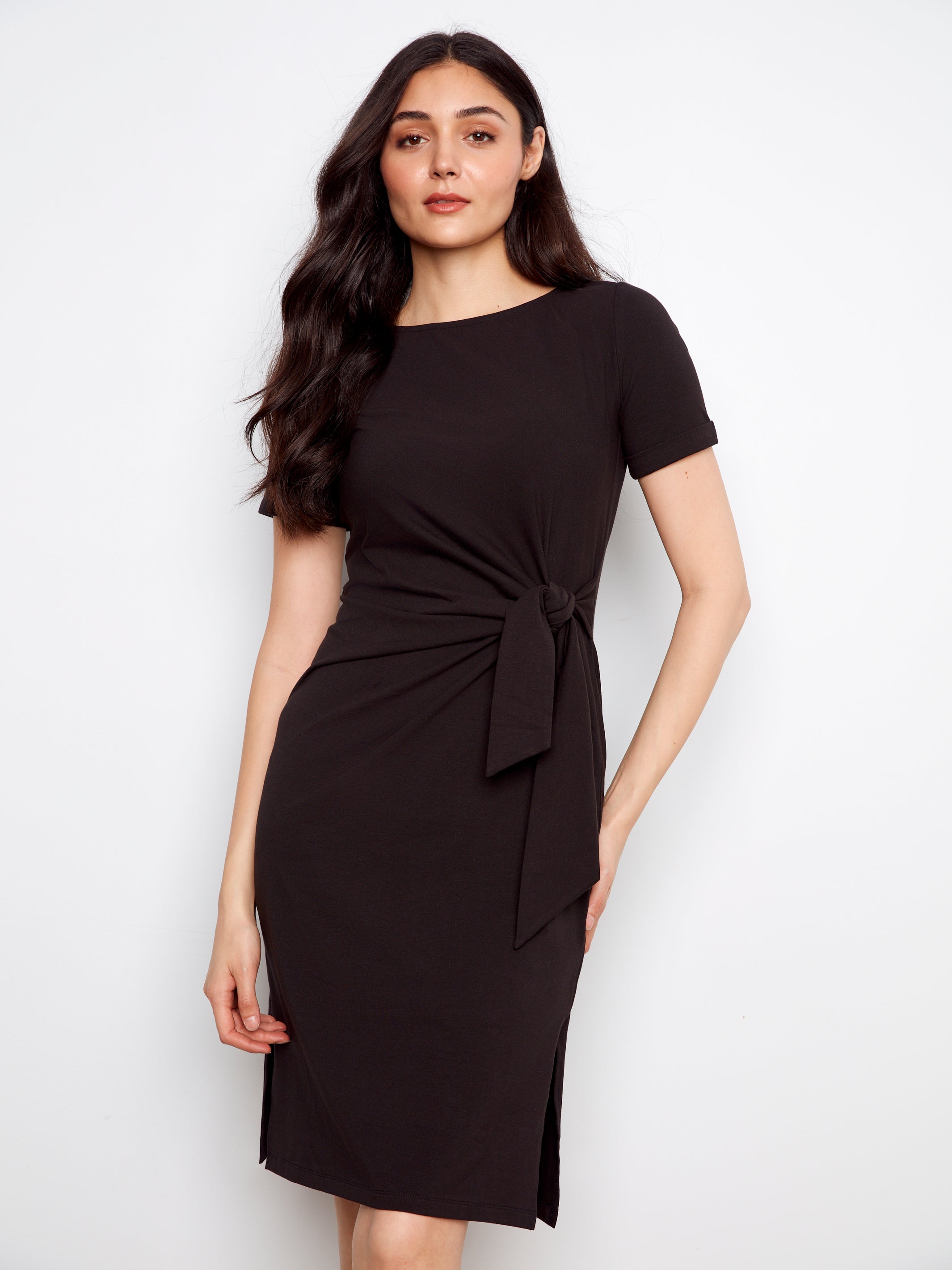 Woman wearing a black dress with a tie waist on a white background