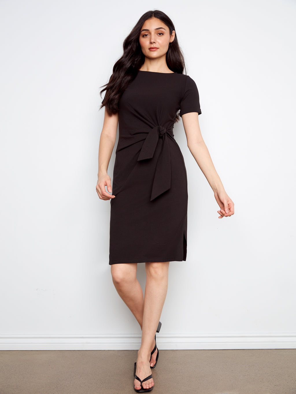 Woman wearing a black dress with a bow detail on a white background