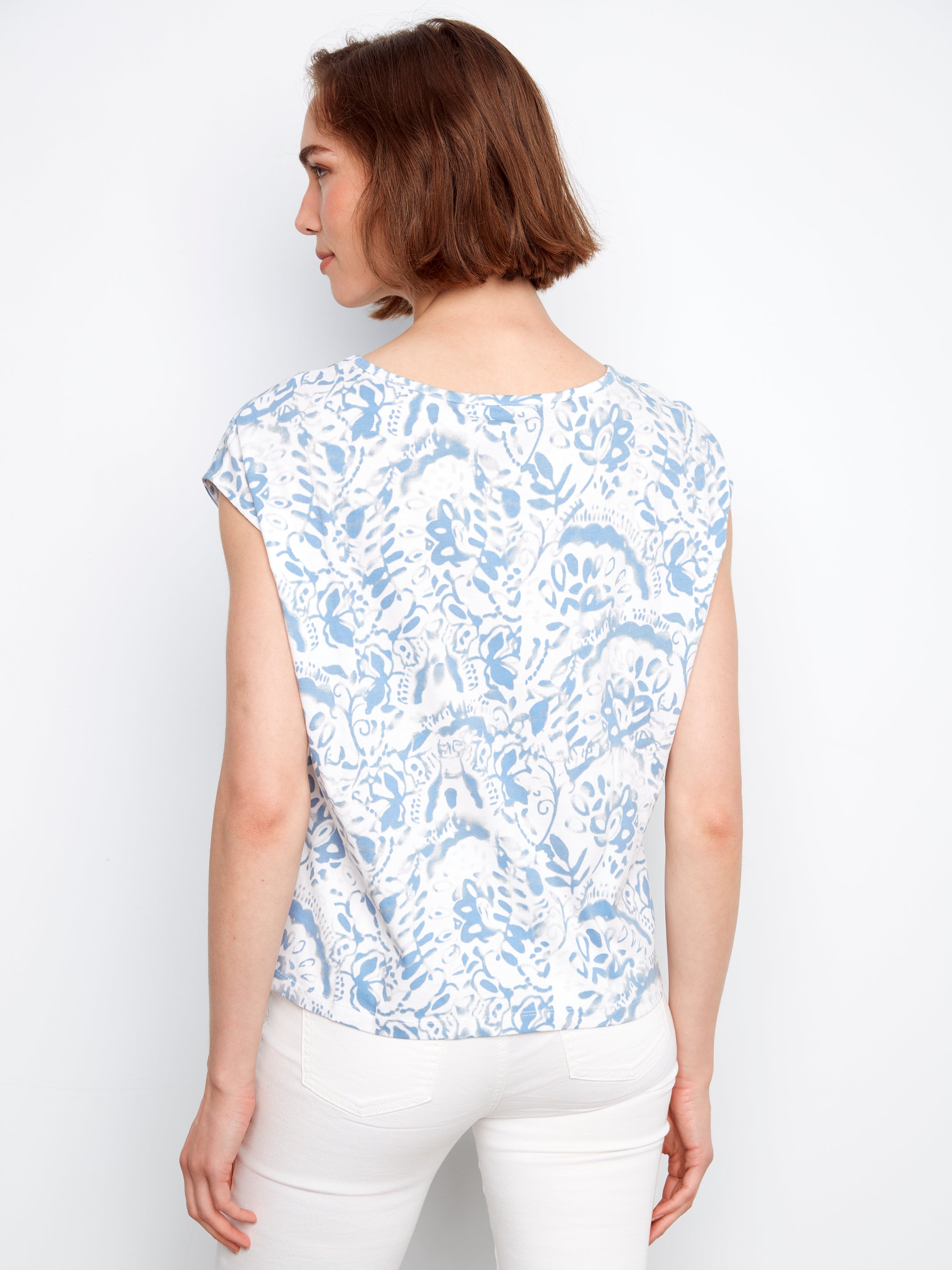 Woman wearing a blue floral patterned top against a white background