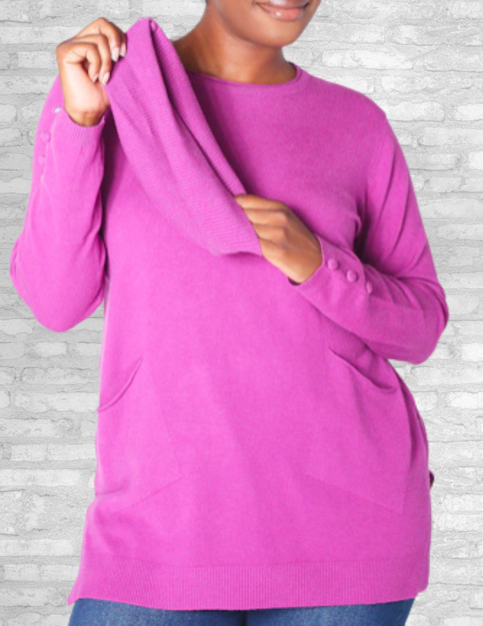 A cozy finely knit tunic in vibrant Grape Punch, featuring a cowl collar with a rolled crew neckline, long sleeves with covered button details, practical front pockets, and a flattering tunic length perfect for layering or pairing with leggings. Stylish and comfortable with a polished finish