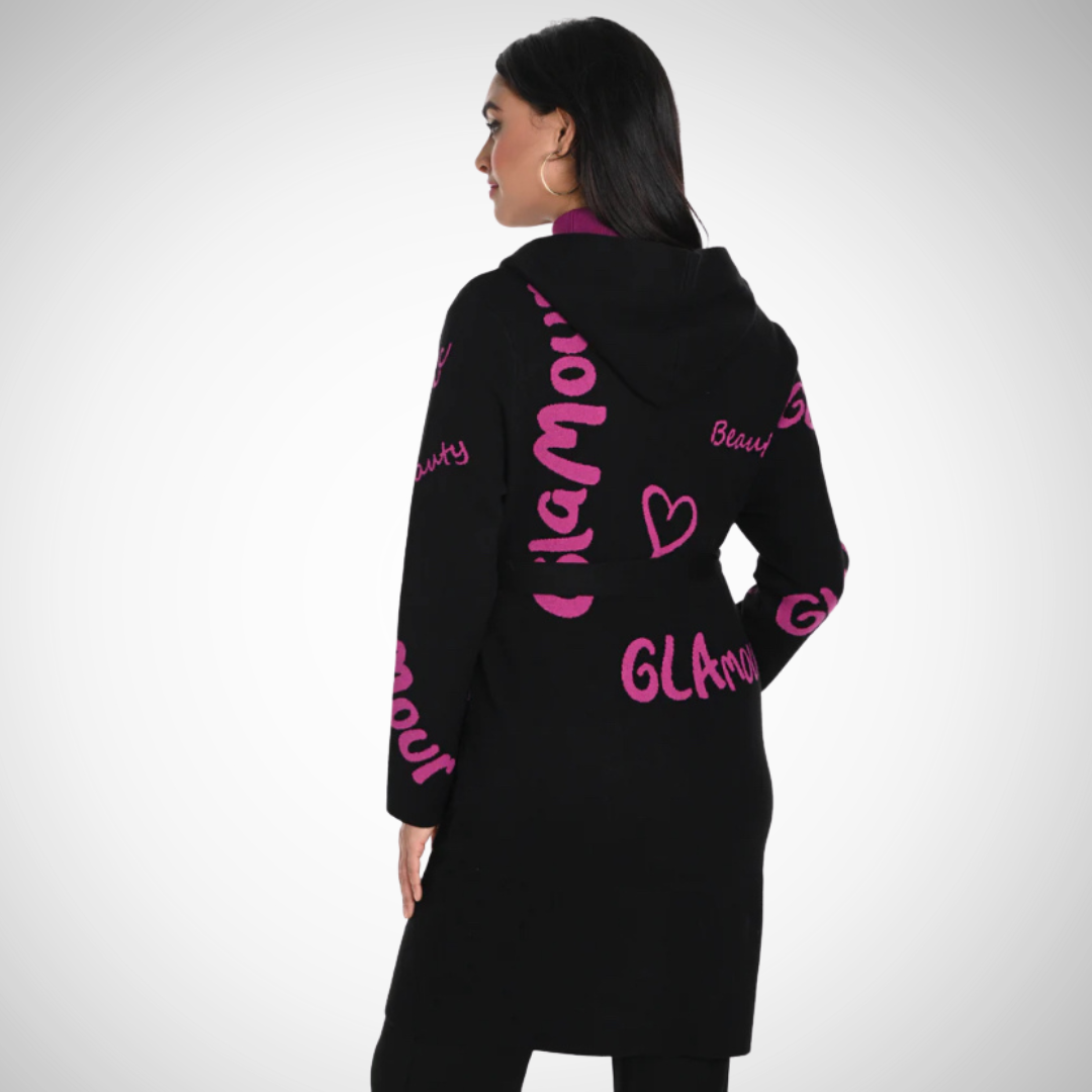 Jaboli Boutique - Fergus Ontario - Frank Lyman - Coatigan. Luxurious cardigan/coat Elevated comfort and stylish design Cozy knit fabric Black and magenta script pattern Hooded Snap closure Belted waist Composition: 48% rayon, 21% nylon, 26% polyester, 5% spandex Perfect for Fall/Winter wardrobe Pairs well with Frank Lyman Faux Leather Leggings