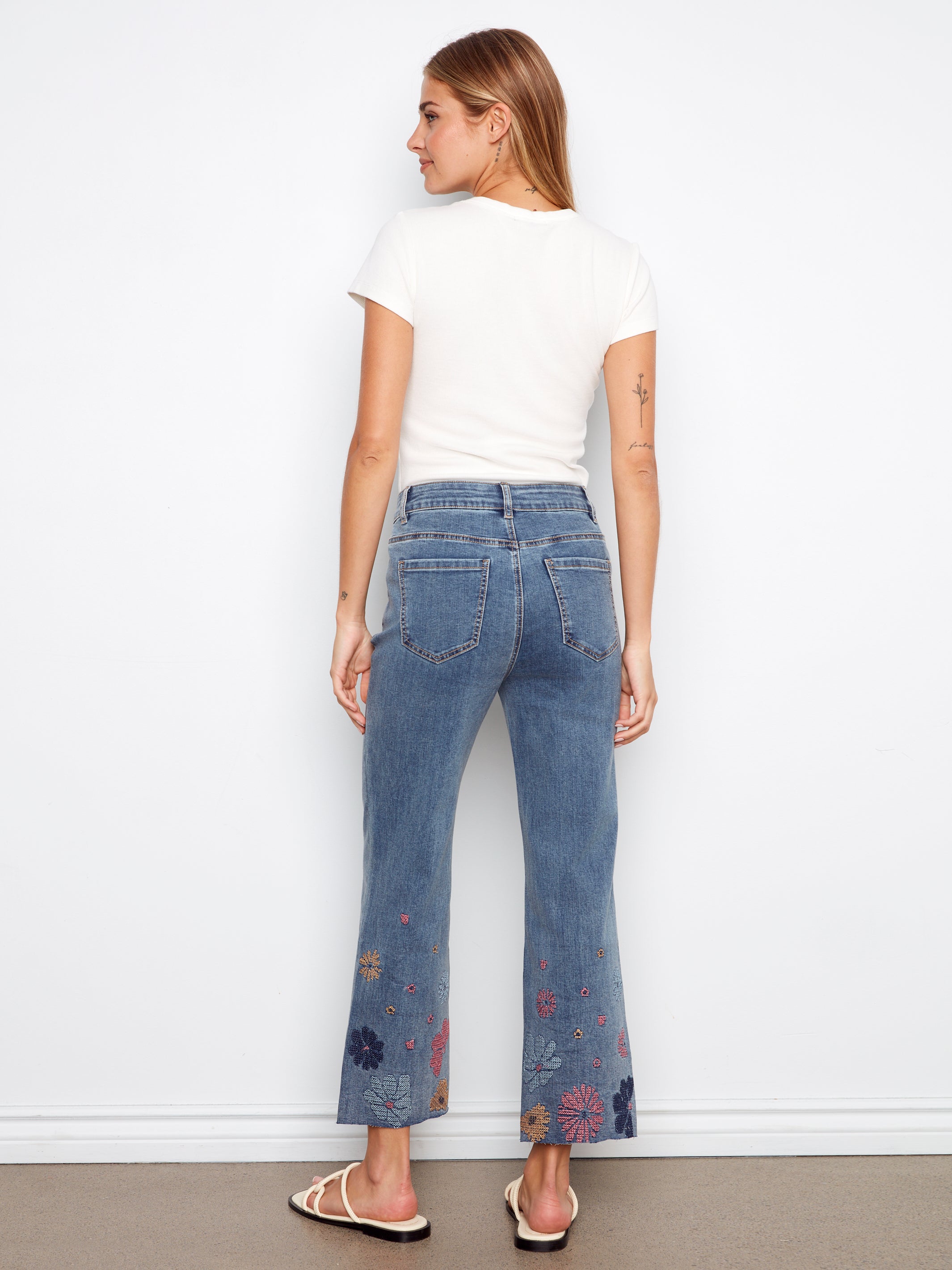 Woman wearing blue jeans with floral patterns on a white background