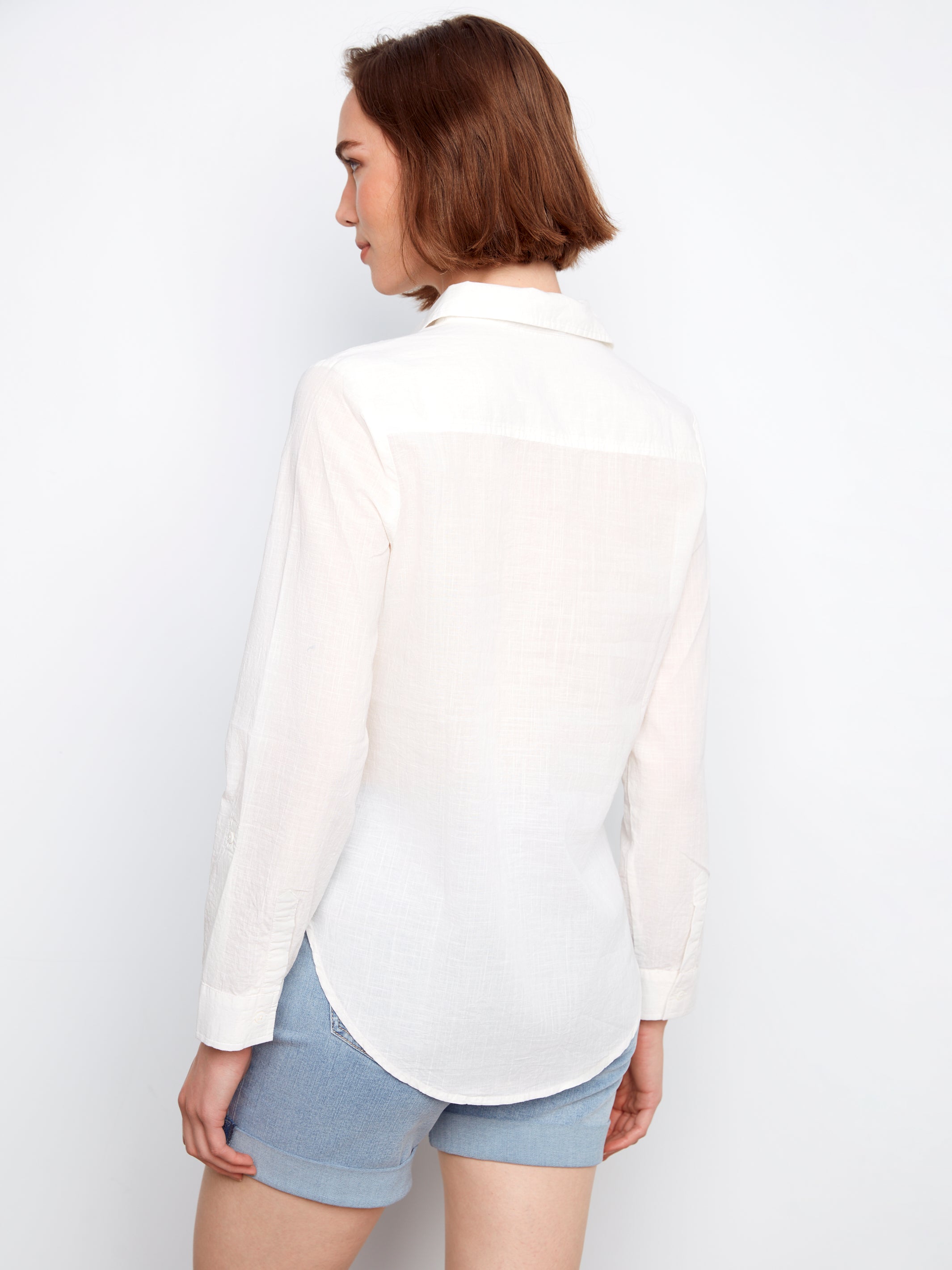 Person wearing a white shirt and light blue shorts on a plain background