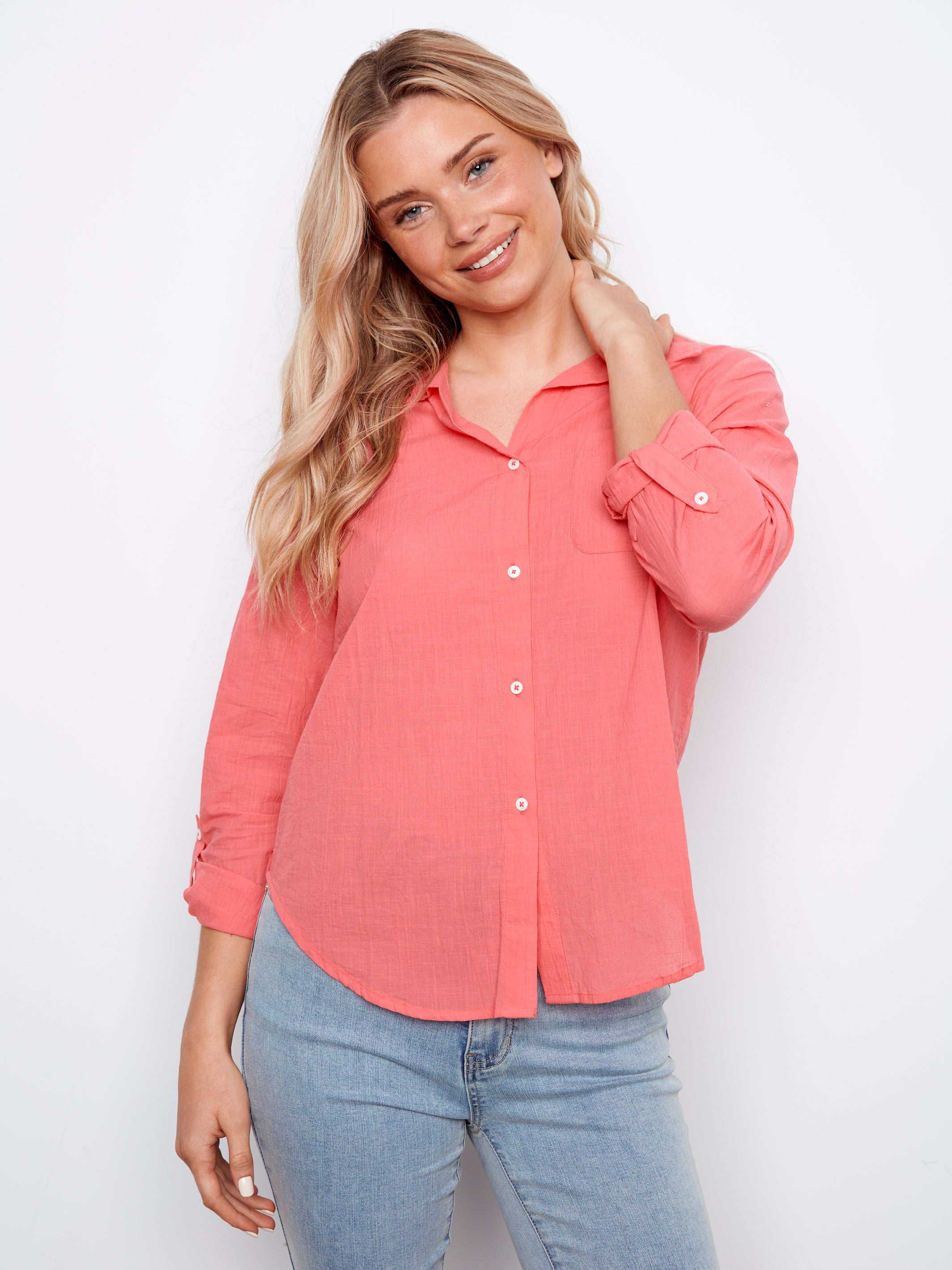 Woman wearing a coral shirt and blue jeans on a white background