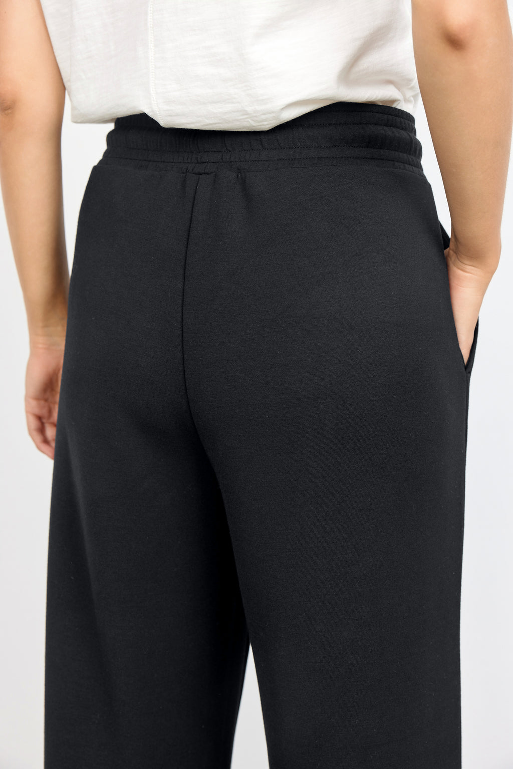 Person wearing black pants and a white top on a light gray background