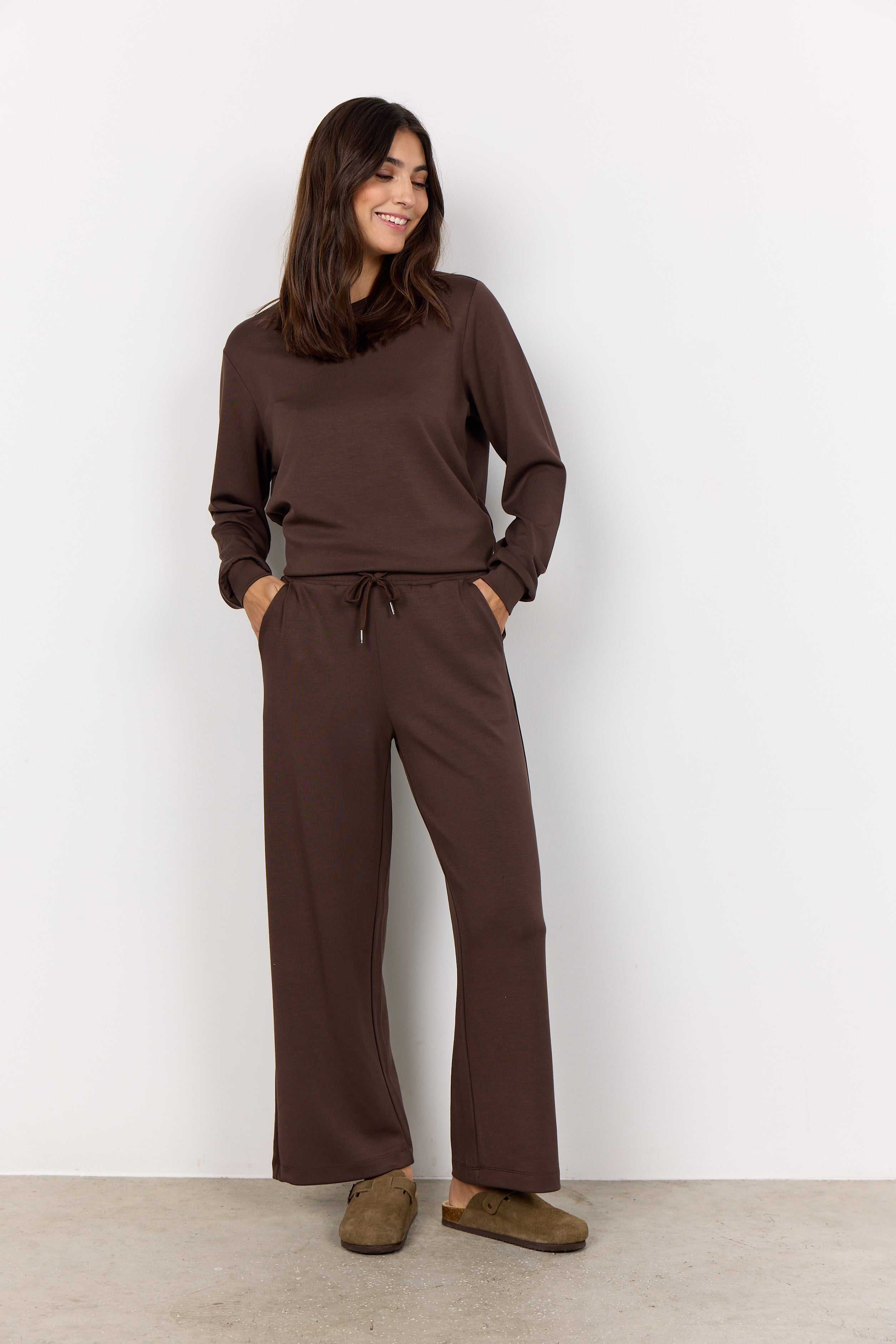 Woman wearing a brown outfit against a white background