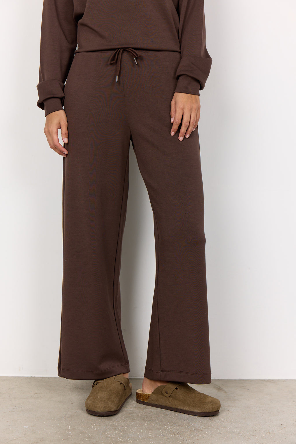 Person wearing brown pants and shoes on a white background