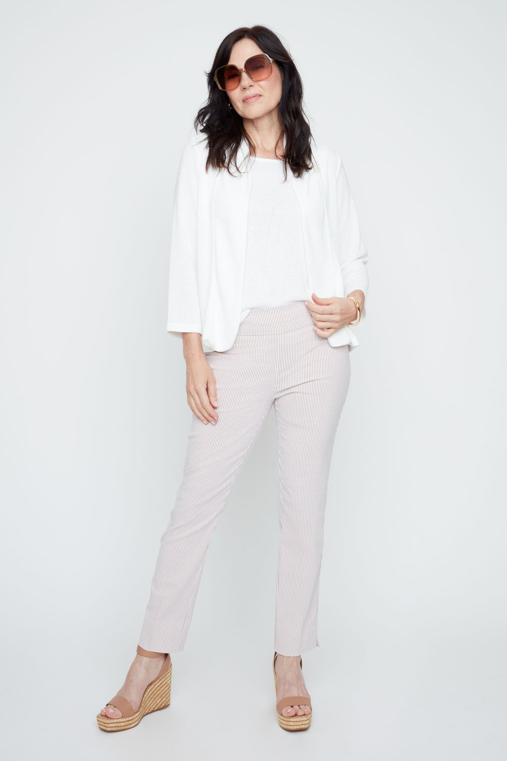 Woman wearing a white outfit with sunglasses on a plain background