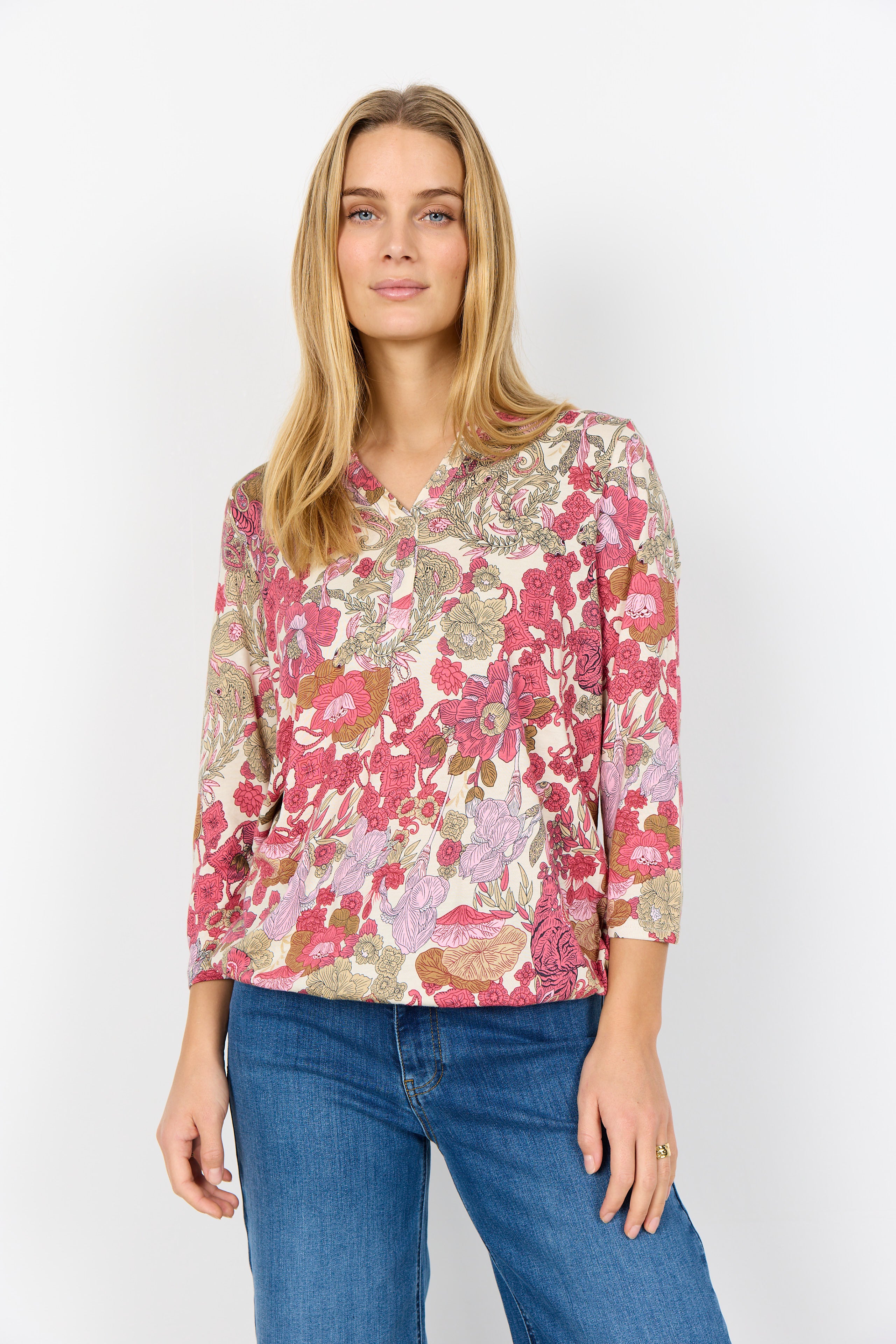 Woman wearing a floral blouse and blue jeans on a white background