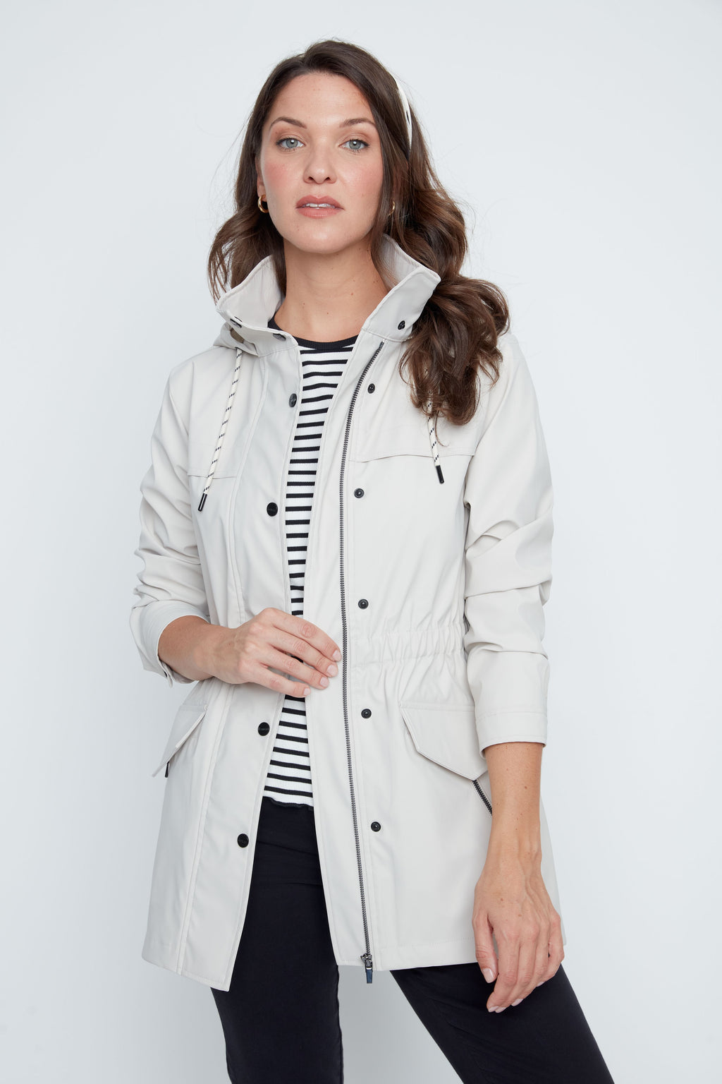 Woman wearing a light gray hooded jacket over a striped shirt on a white background