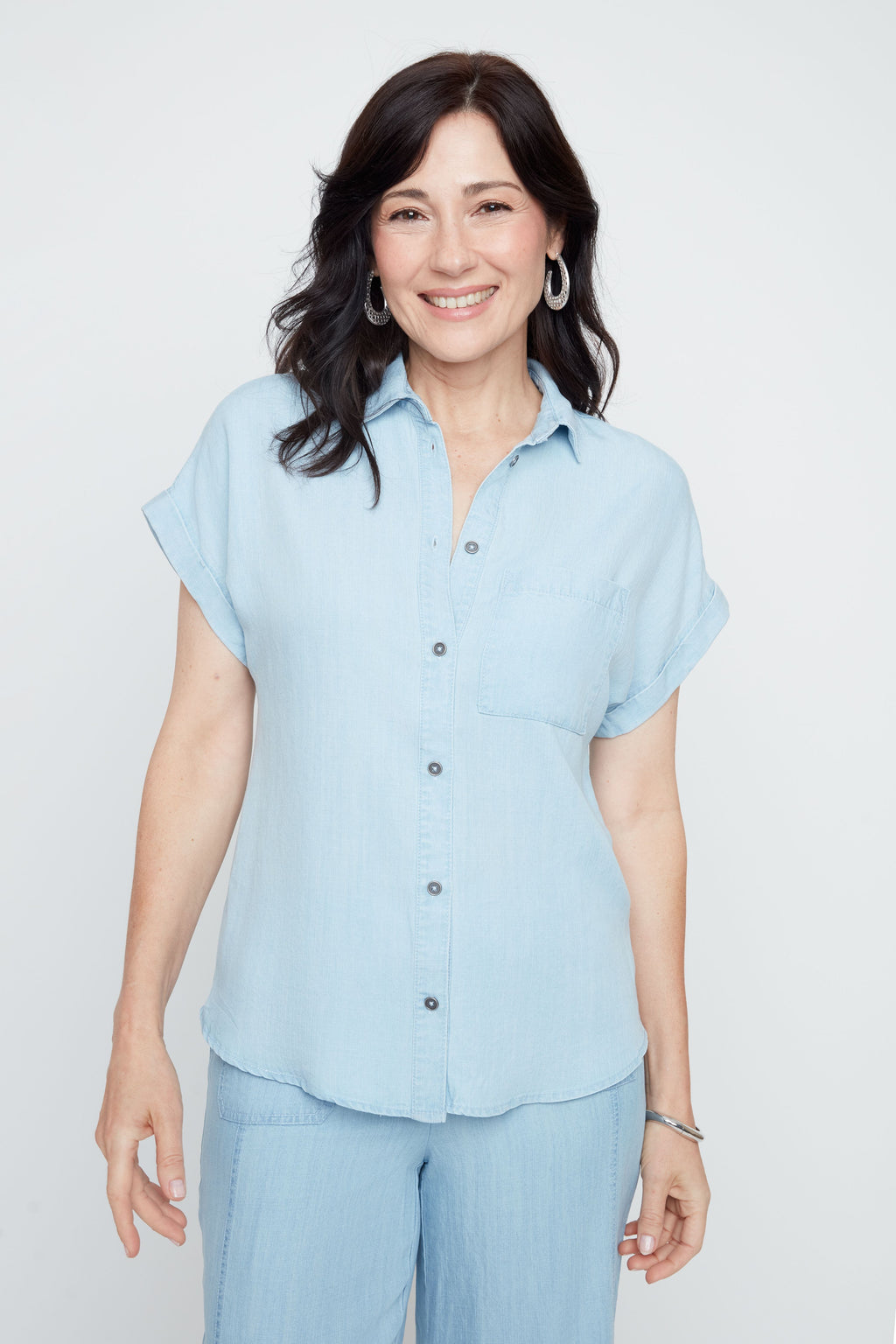 Woman wearing a light blue shirt and pants on a white background