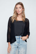 Woman wearing a black mesh top and light blue jeans against a white background