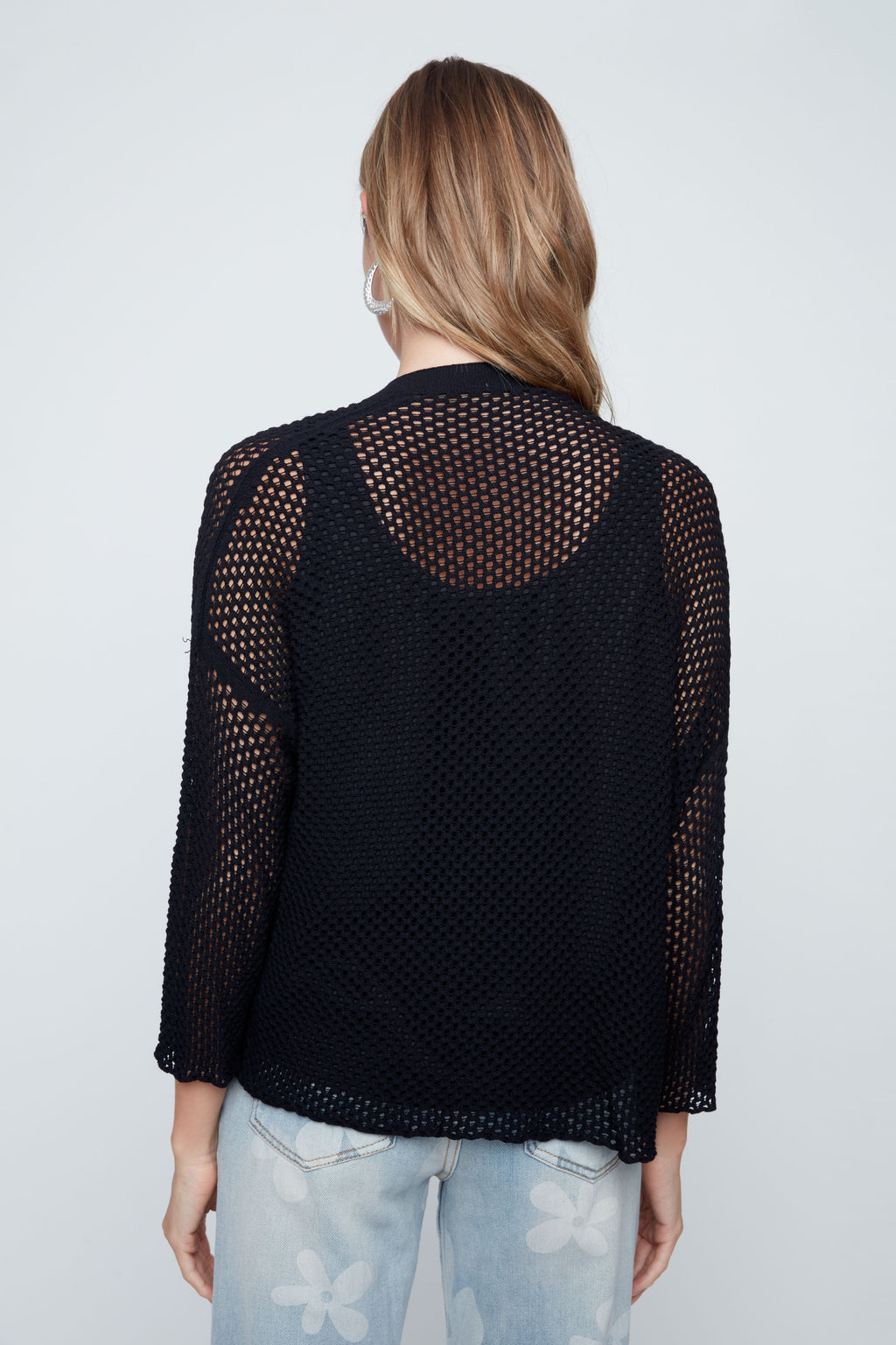 Person wearing a black mesh top with a plain background