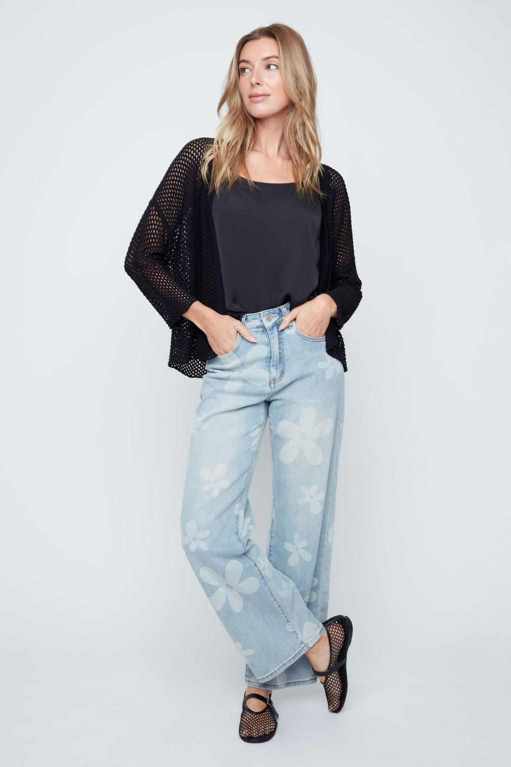 Woman wearing a black top and light blue jeans on a white background