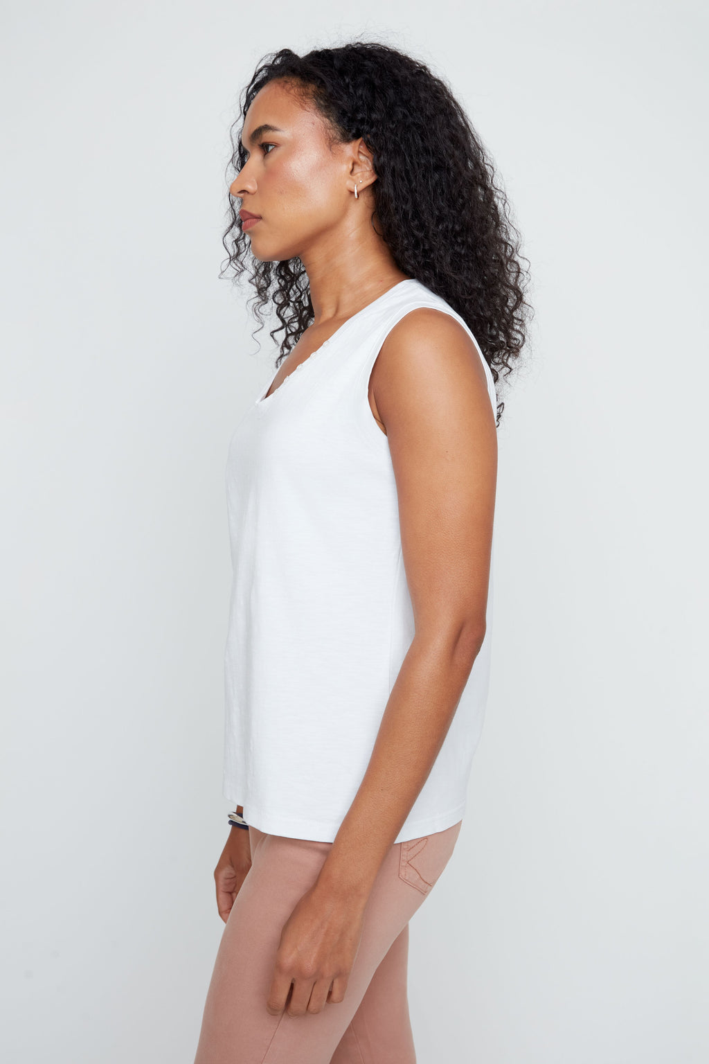 Woman wearing a white sleeveless top against a plain background